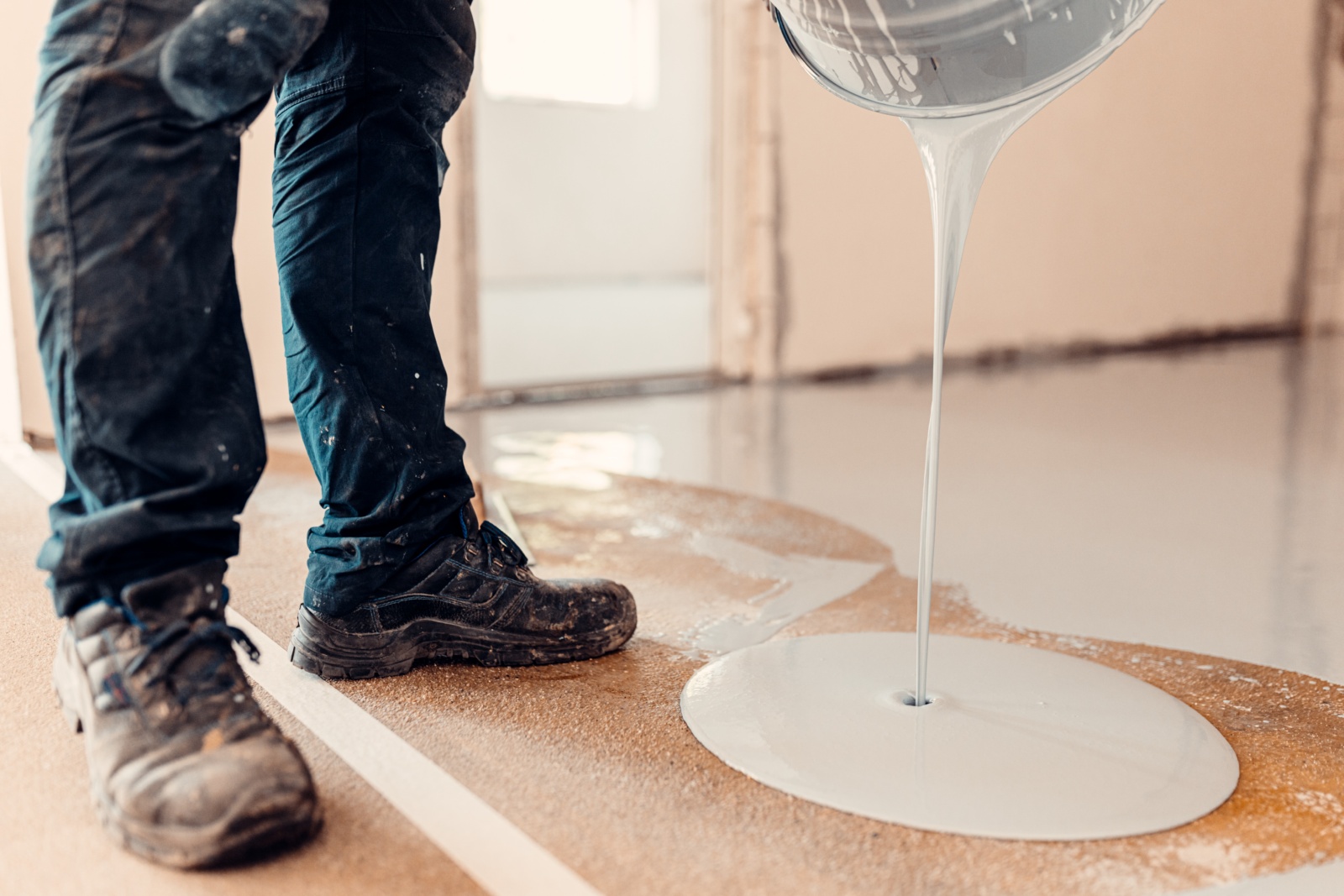 Adhesive being poured onto a subfloor before flooring installation